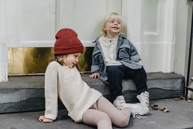 Två små barn som sitter på en trappa utanför en ytterdörr