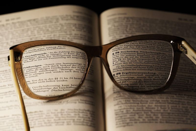 Läsglasögon som förstorar tät, finstilt text i en uppslagen bok